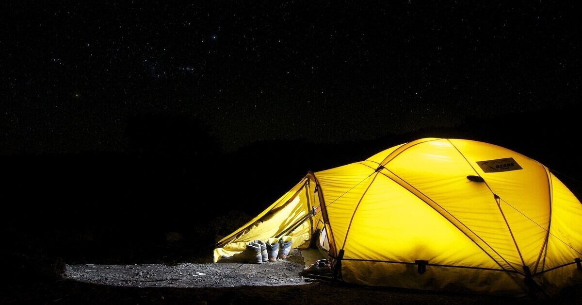 Illuminated yellow tent with shoes at entrance