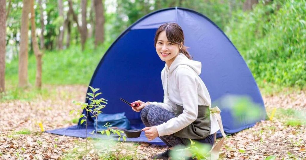 Solo camper squating next to her tent